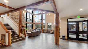 A spacious lobby with a stone wall, wooden staircase, and a large glass door labeled "EXIT".
