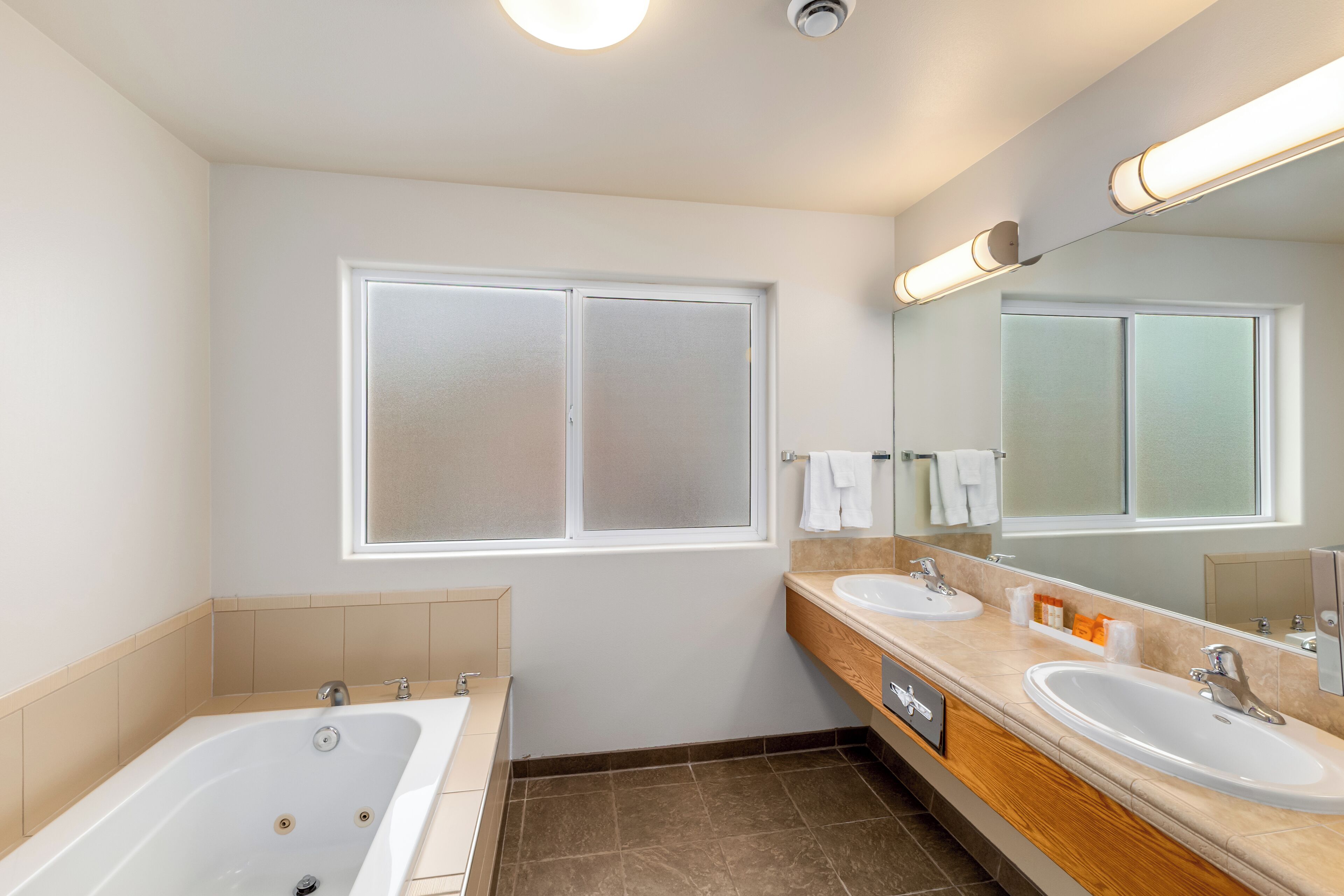 Un baño moderno con dos lavamanos, una bañera y un espejo grande.