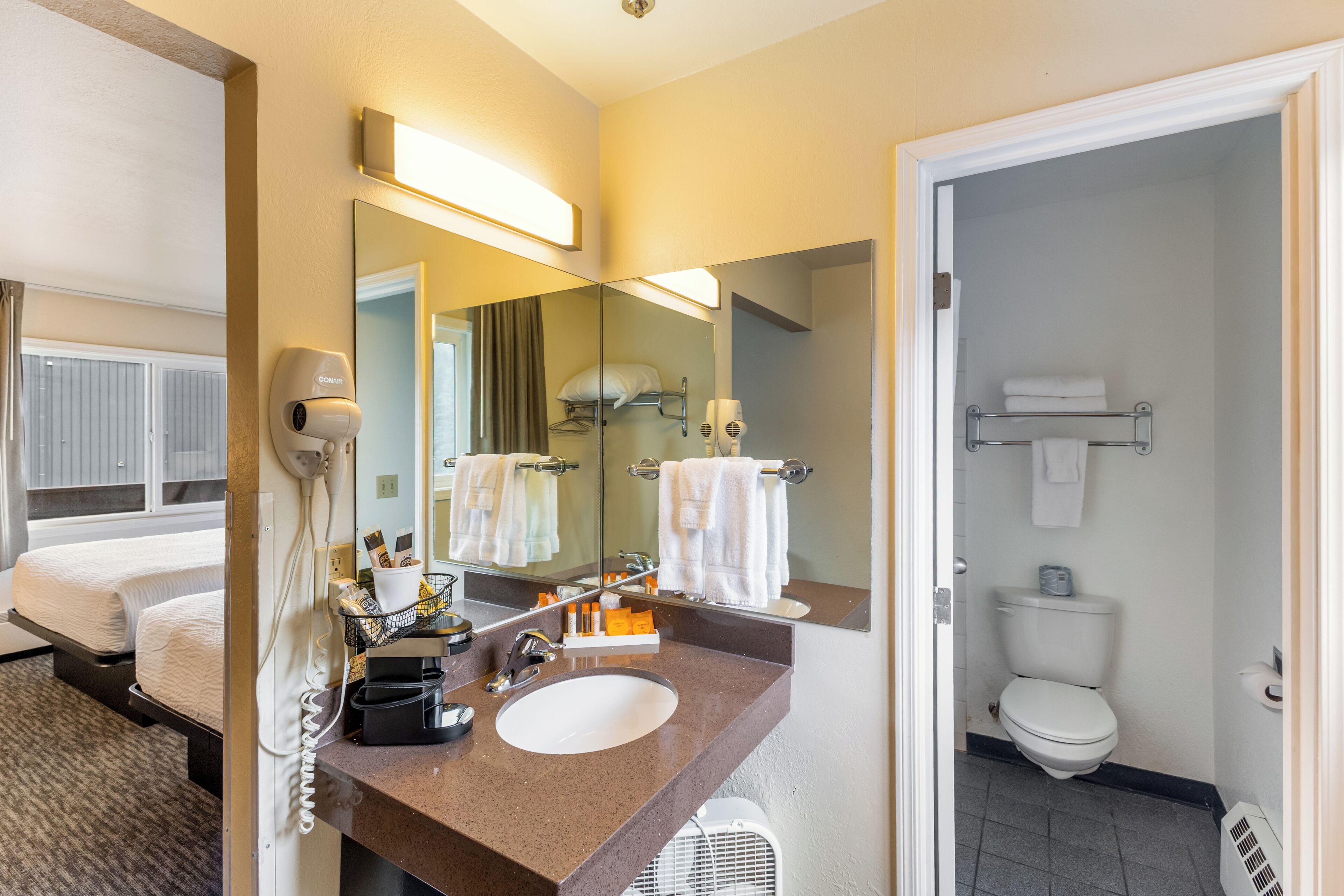 Une salle de bain d’hôtel équipée d’un lavabo, d’un miroir et d’articles de toilette.