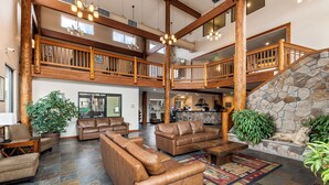 A spacious lobby with leather sofas, a stone fireplace, and a wooden staircase.