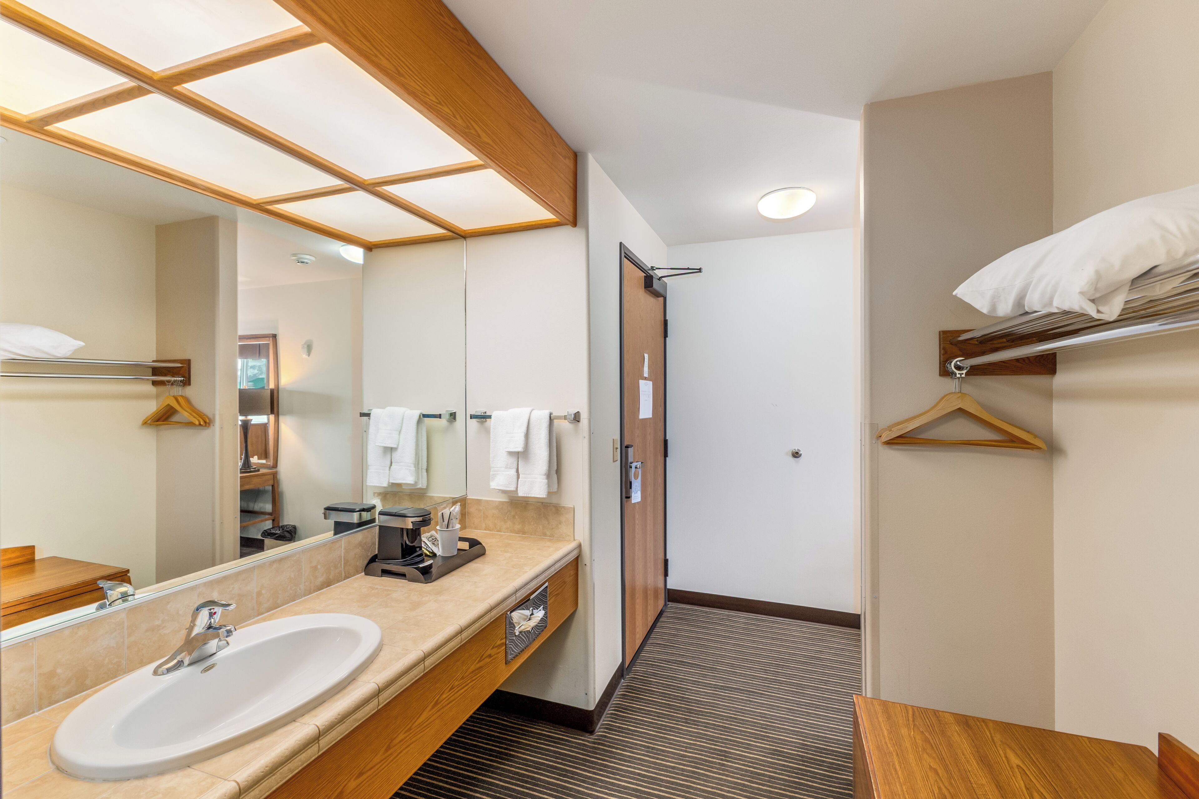 A modern bathroom with a large sink, mirror, and towel rack.