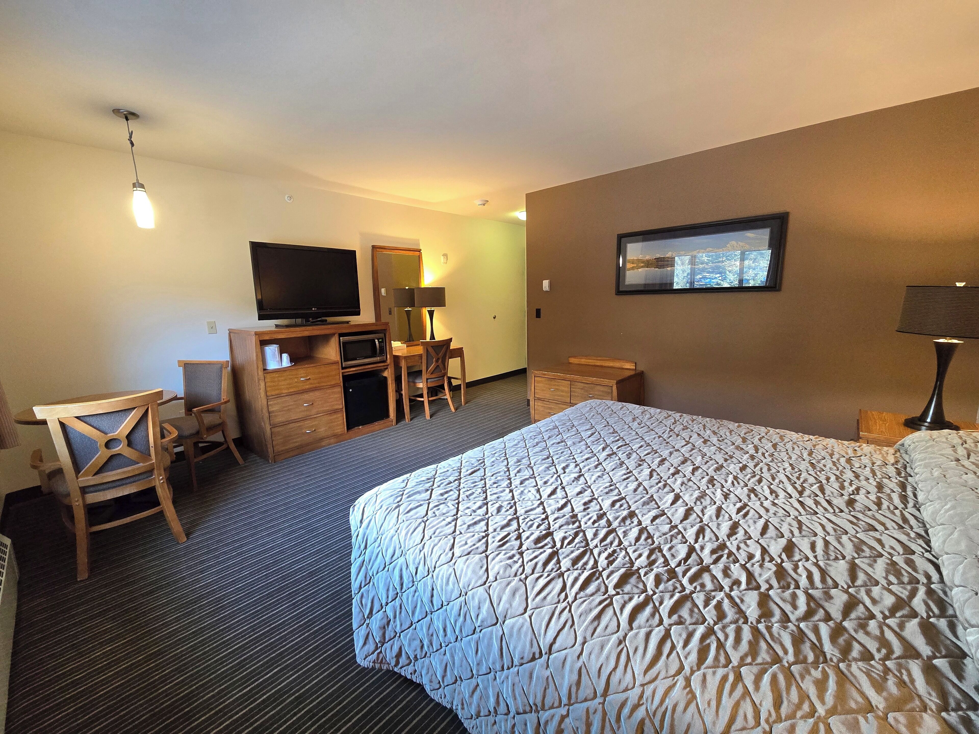 A hotel room with a bed, a desk with a computer, a television, and a window with a city view.