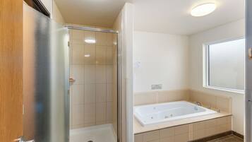 Une salle de bain avec une douche à parois de verre, une baignoire et une fenêtre.