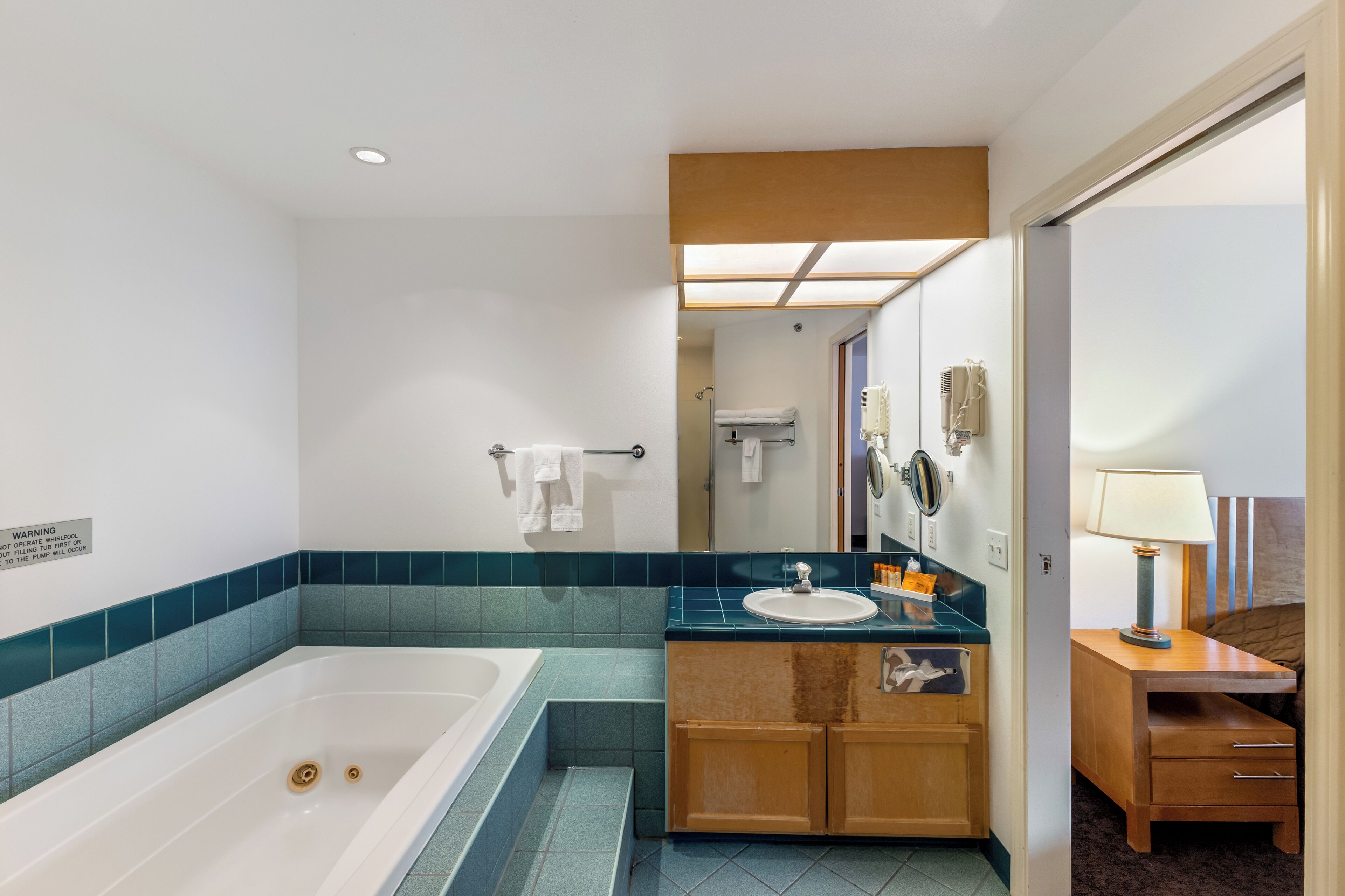 A modern bathroom with a large bathtub, a sink, and a vanity with a mirror.