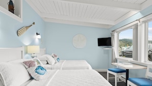 A hotel room with two beds, a desk with a chair, a TV, and a window with a view of the outside. - Harborview Inn & RV Park (Garibaldi)