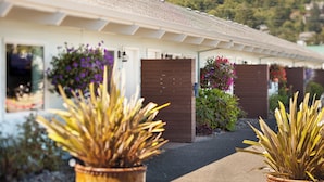 A building with a white facade, a brown door, and potted plants in the foreground. - Harborview Inn & RV Park (Garibaldi)