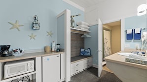 A compact kitchen with a microwave, coffee maker, and fan. A small sink and storage cabinets are also visible. - Harborview Inn & RV Park (Garibaldi)