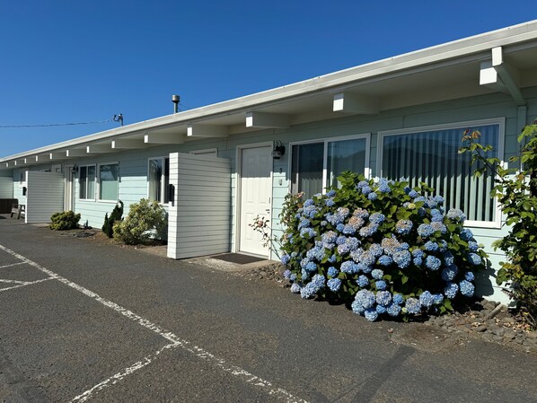 A motel with a row of single-story buildings, each with a garage door and a small porch area.