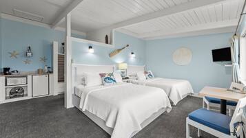 Un dormitorio con dos camas, un escritorio, una silla, un televisor y una kitchenette.