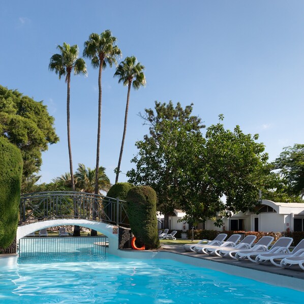Una piscina al aire libre, sillones reclinables de piscina
