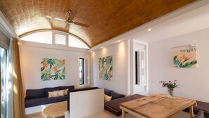 A modern living room with a wooden ceiling, a sofa, a dining table, and artwork on the walls. - Bungalows Cordial Biarritz (San Bartolomé de Tirajana)