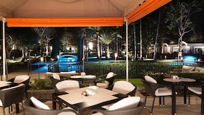 An outdoor patio area with tables and chairs, a pool, and a bridge. - Bungalows Cordial Biarritz (San Bartolomé de Tirajana)