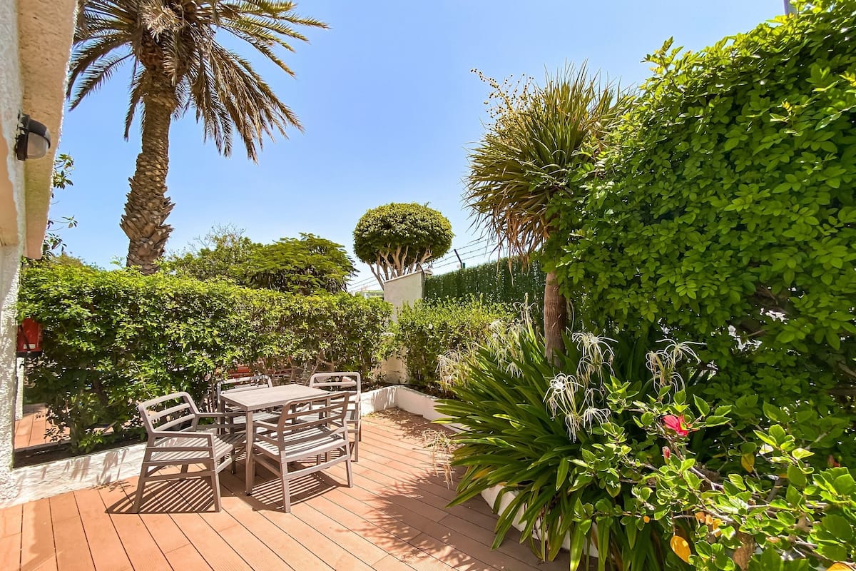 An outdoor patio with a wooden deck, metal chairs, and a table.