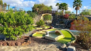 A landscaped garden with a bridge, water features, and tropical plants. - Bungalows Cordial Biarritz (San Bartolomé de Tirajana)