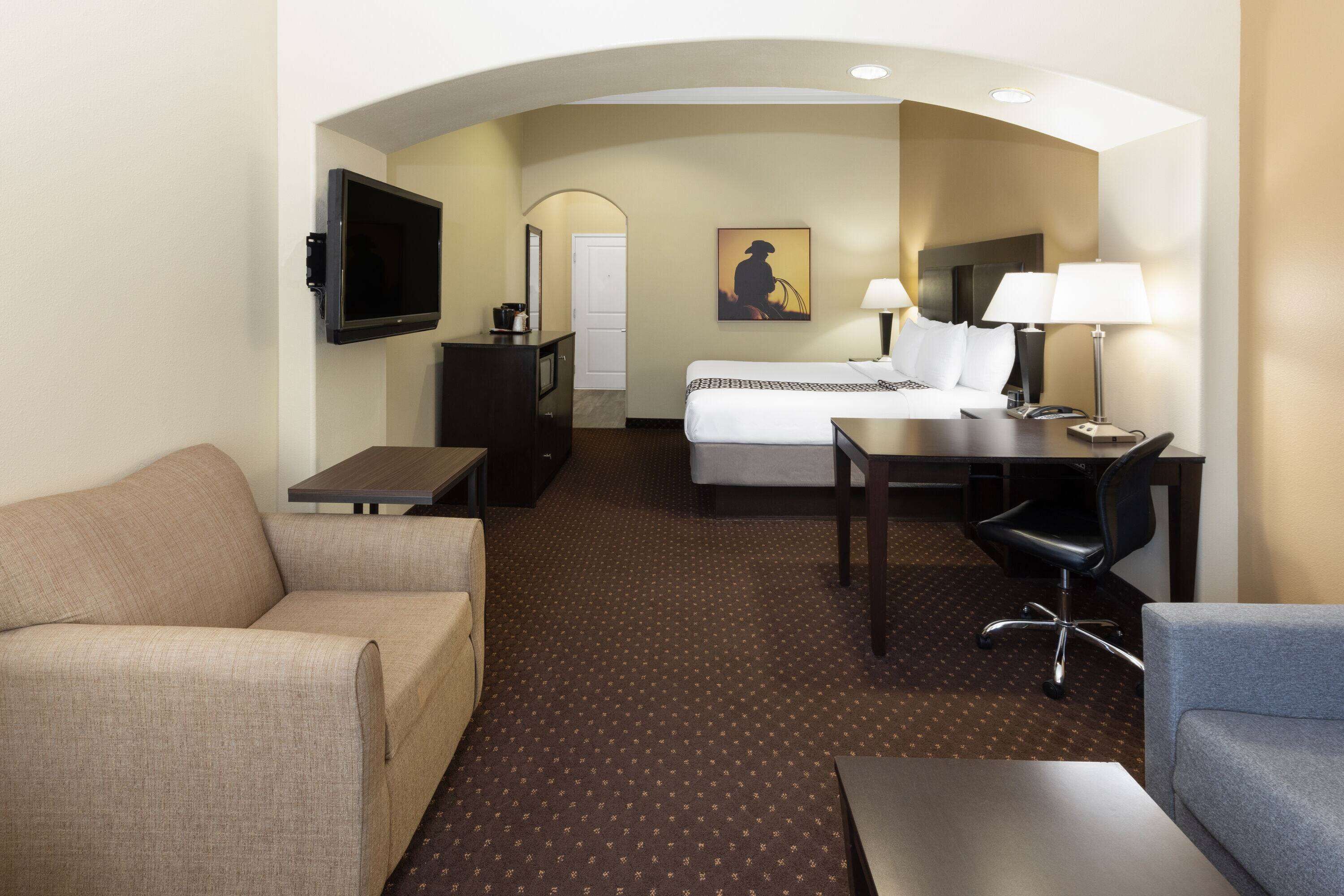 Une chambre d’hôtel équipée d’un lit, d’un bureau, d’une chaise, d’un canapé et d’une télévision.
