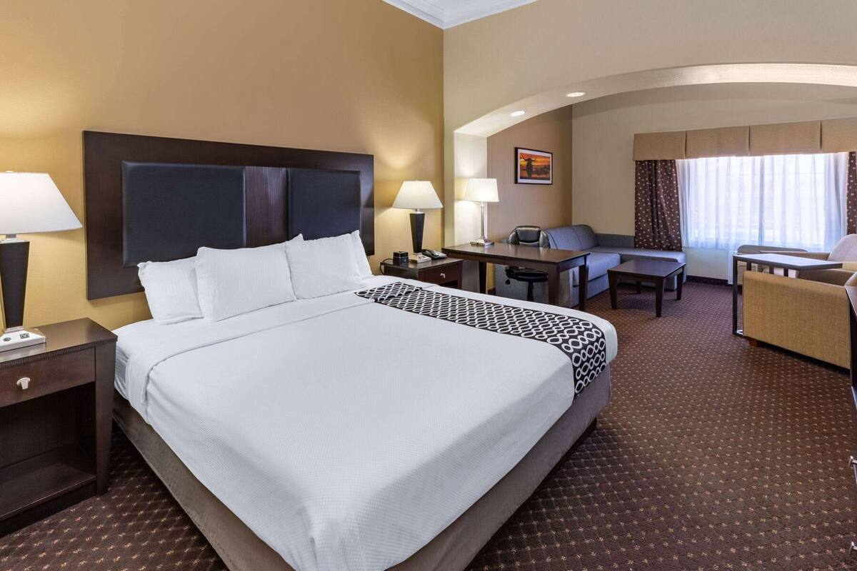 A hotel room with a large bed, a desk, a chair, and a sofa.