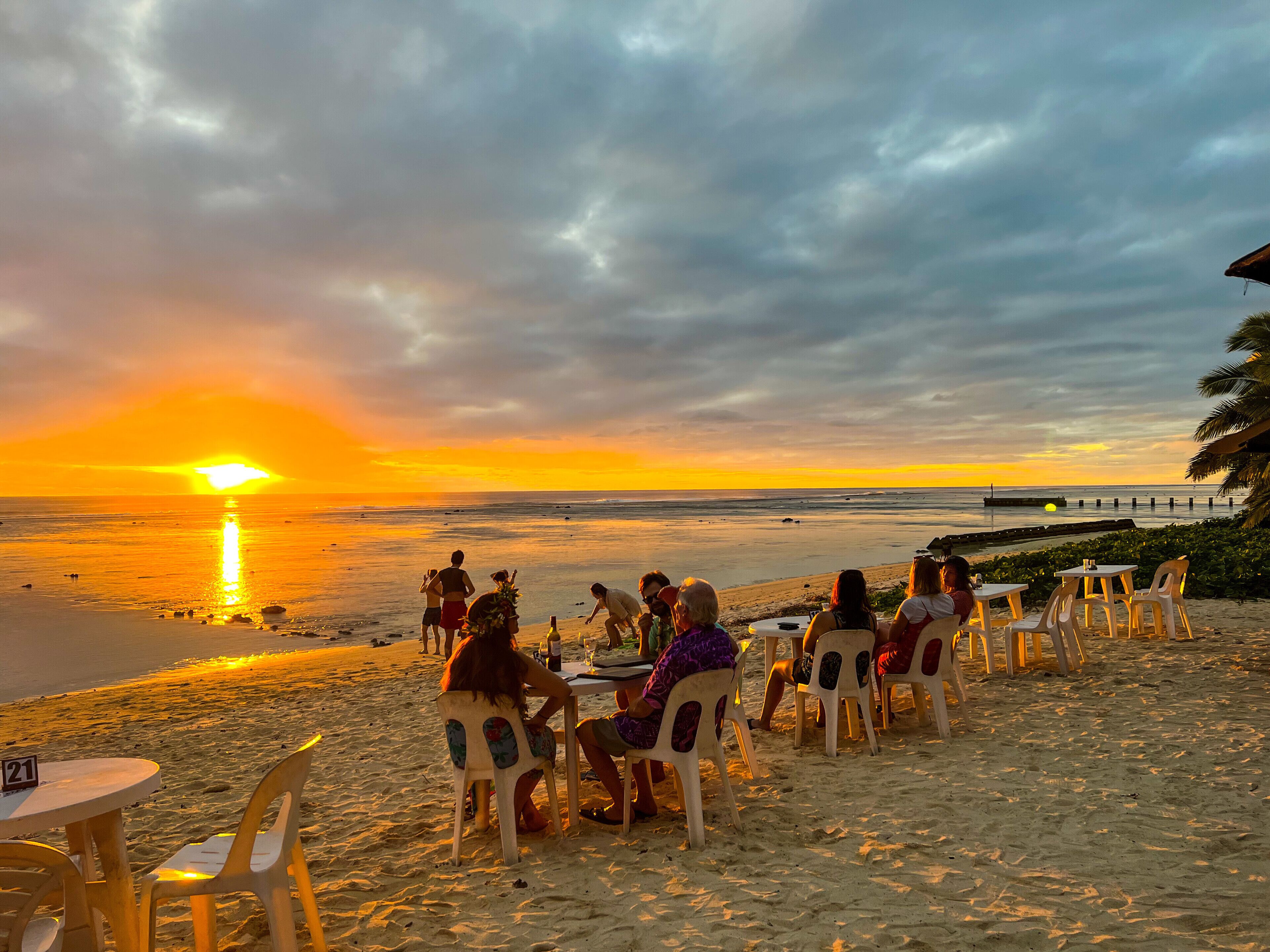 Un restaurante frente al mar con terraza al aire libre, mostrando una vista del atardecer.