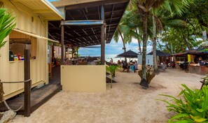 A beachside restaurant with outdoor seating, a covered area, and a view of the ocean. - Castaway Resort (Rarotonga)