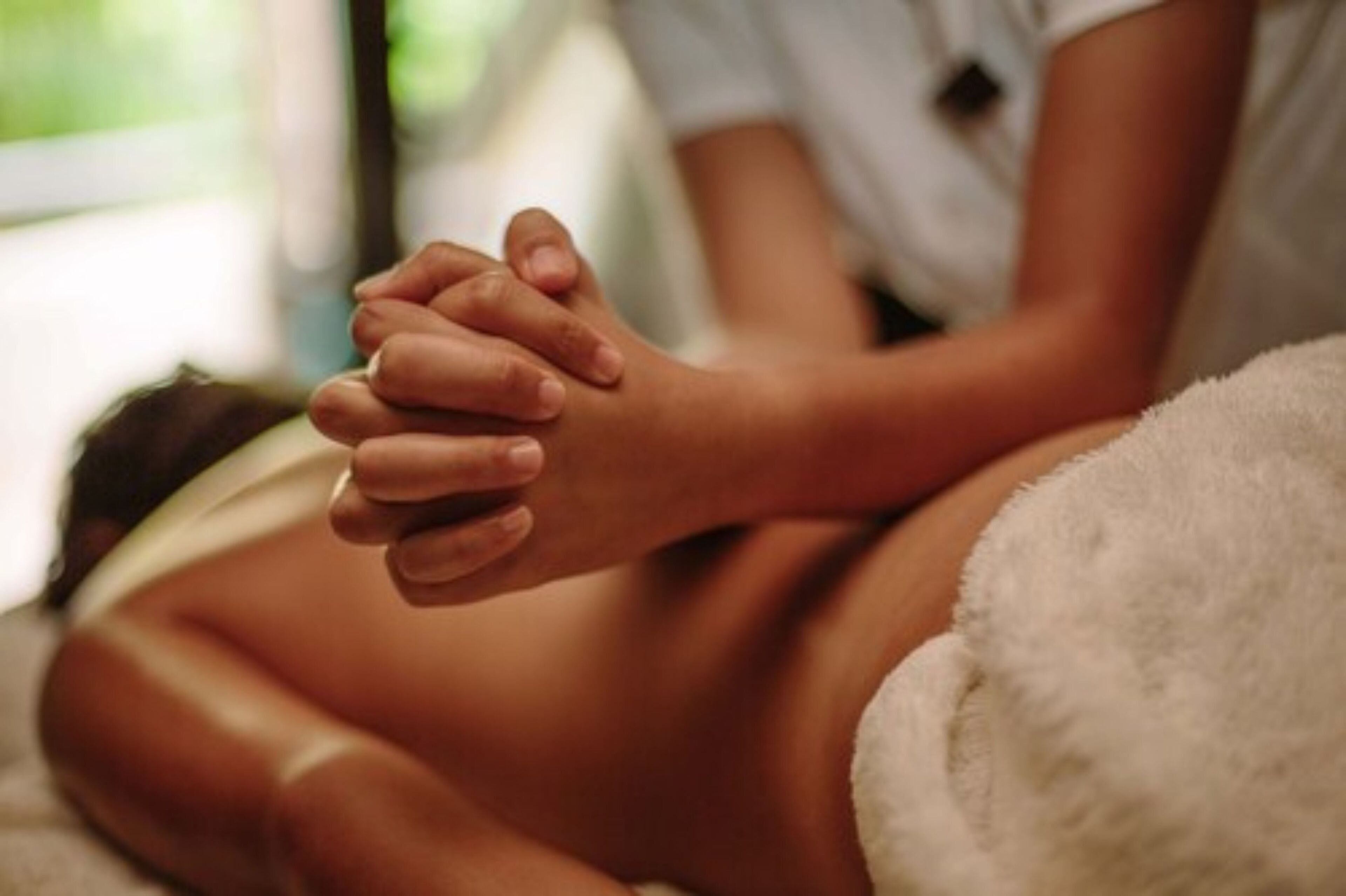 A close-up of a person's hands clasped together, resting on a white, fluffy surface.
