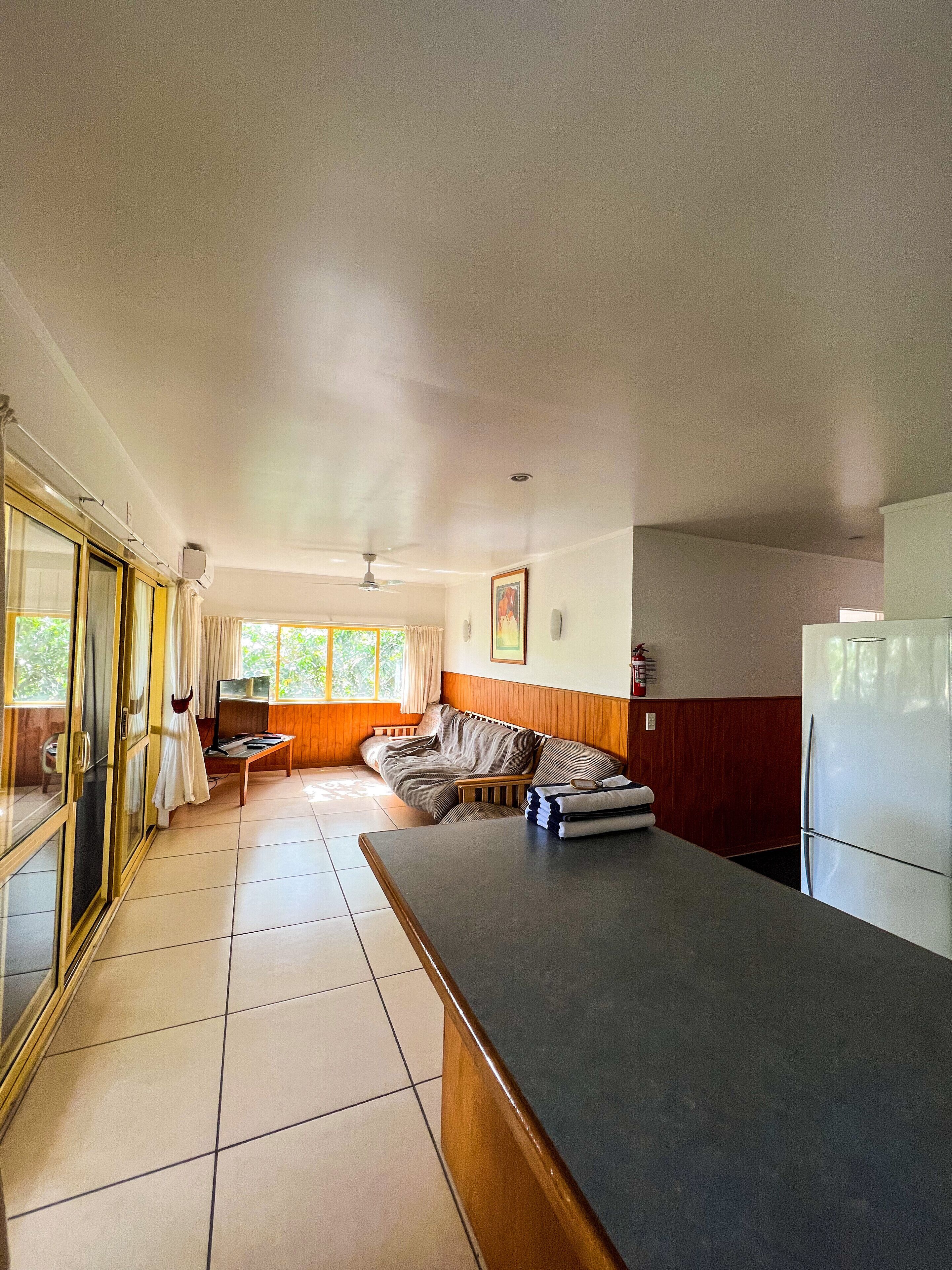 A spacious living area with a sofa, a dining table, and a kitchen area including a refrigerator.