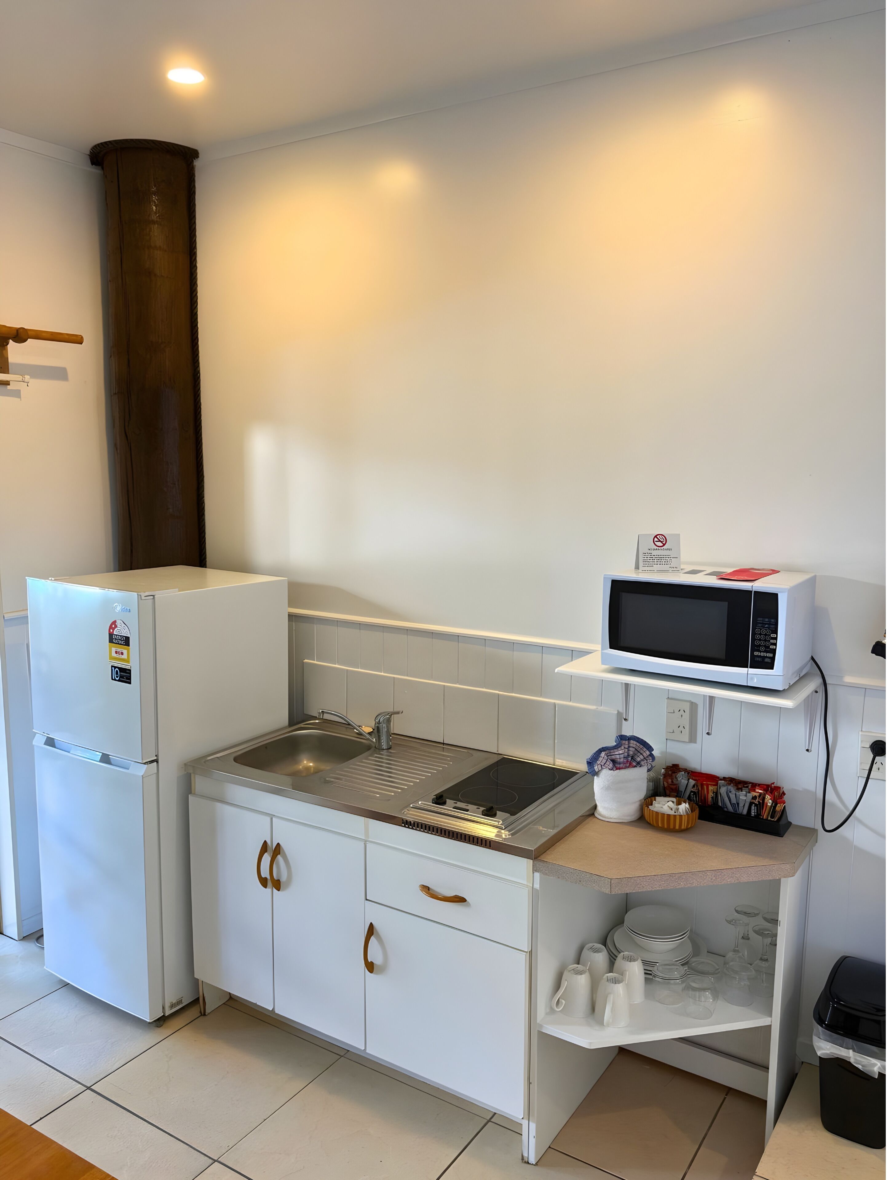 A compact kitchen with a refrigerator, stove, sink, microwave, and a small countertop with storage.
