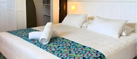 A neatly made bed with white linens and a colorful floral bedspread.