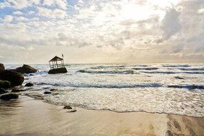 Une plage avec une petite construction, peut-être un poste de surveillance pour les sauveteurs, située près du bord de l’eau.