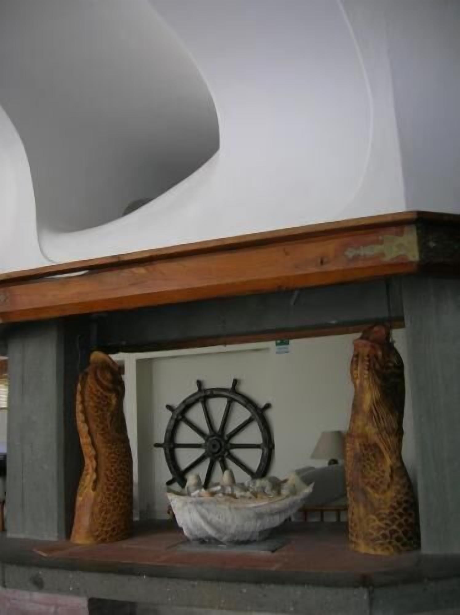 A room with a unique ceiling design, a ship's wheel, and two decorative animal figures.