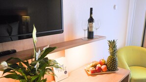 A hotel reception area with a wooden counter, a potted plant, a bottle of wine, a tray of fruit, and a chair. - Landgasthof zur Blume (Lichtenau-Scherzheim)