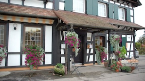 A traditional half-timbered building with hanging flower baskets and a bench outside. - Landgasthof zur Blume (Lichtenau-Scherzheim)