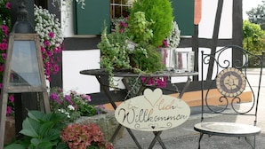 A welcoming sign with a heart and a flower, surrounded by potted plants and flowers. - Landgasthof zur Blume (Lichtenau-Scherzheim)