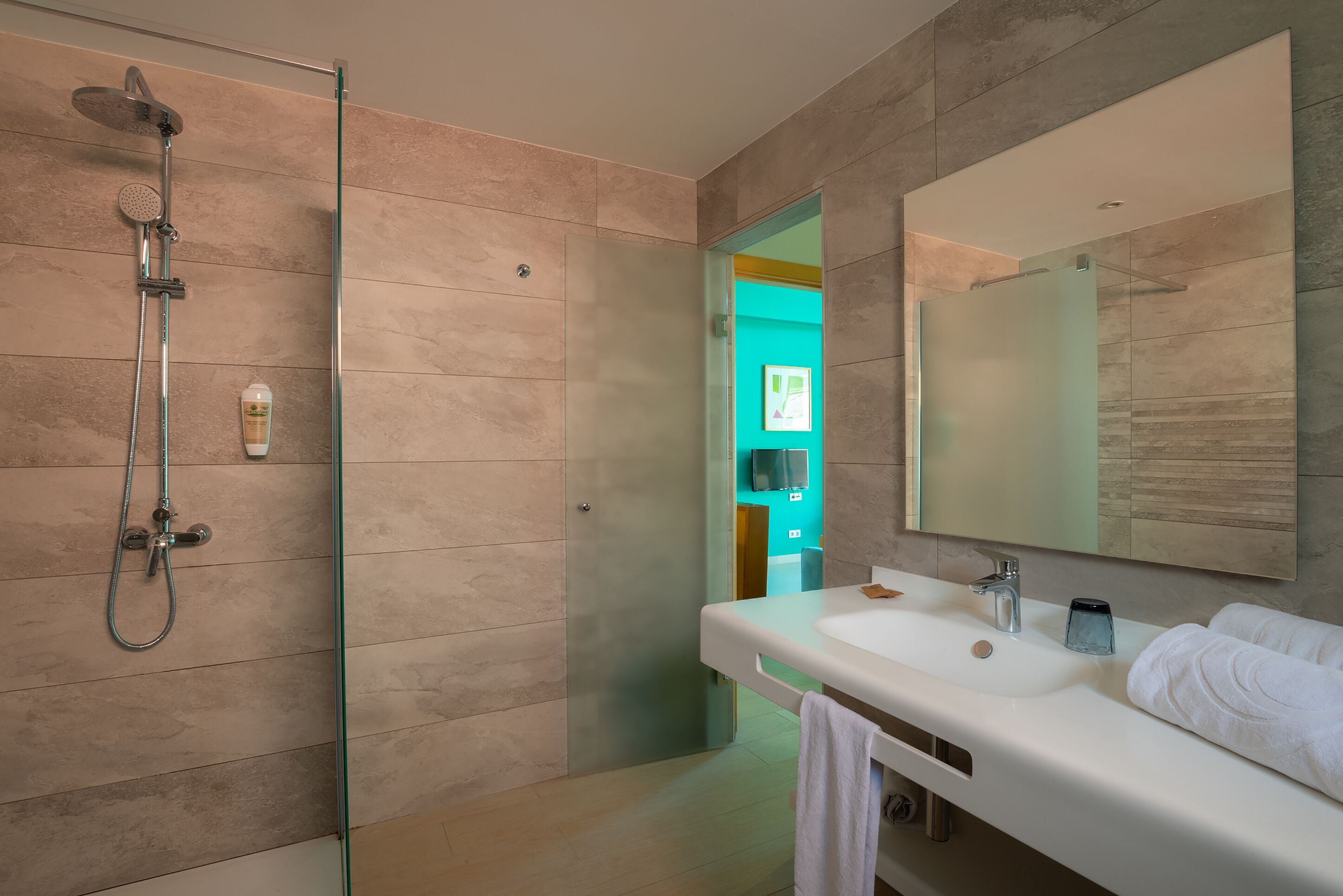A modern bathroom with a glass-enclosed shower, a large mirror, and a white sink with a towel.