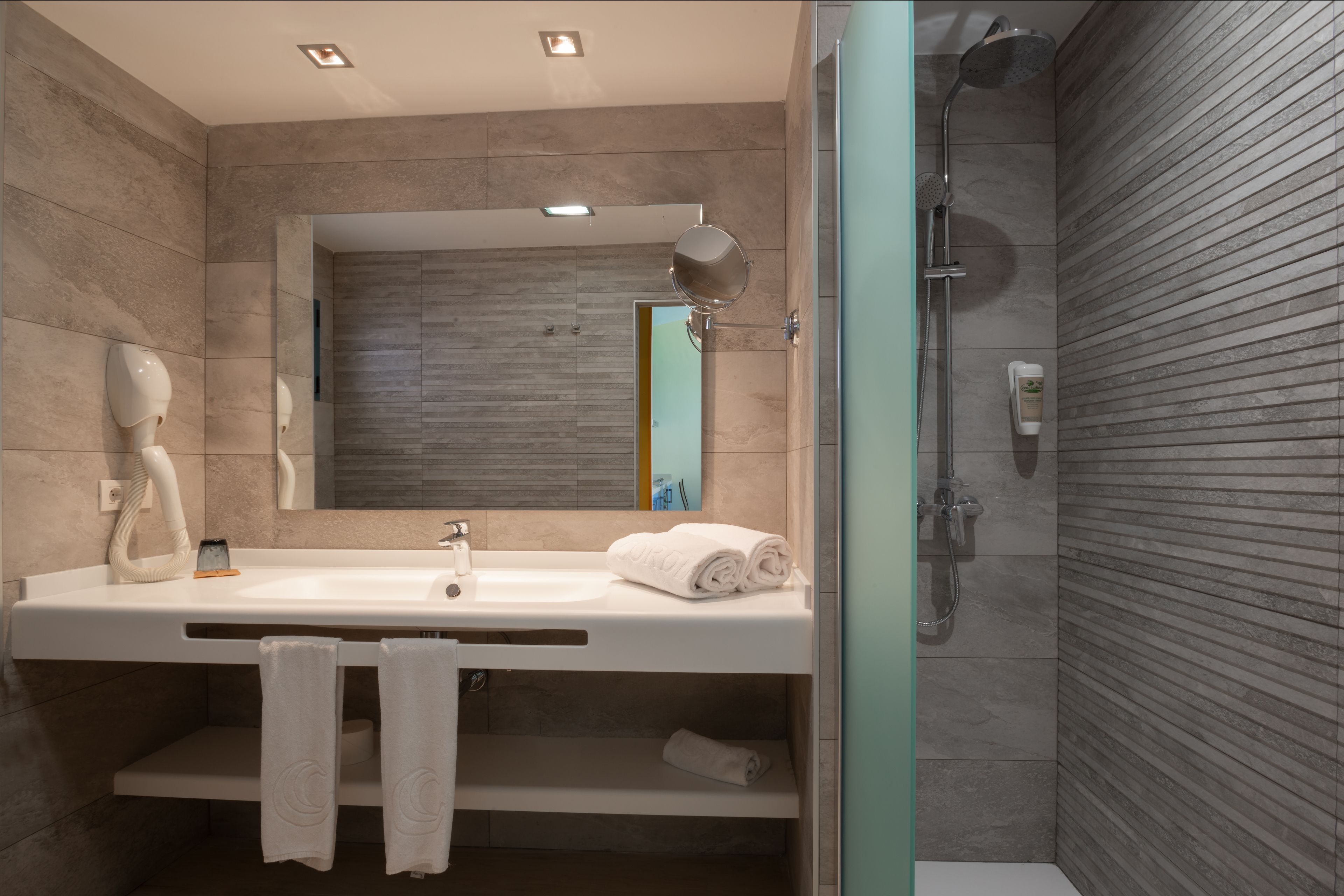 A modern bathroom with a large sink, mirror, and shower.