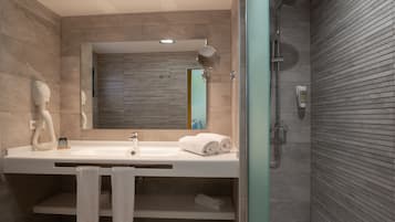A modern bathroom with a large sink, mirror, and shower.