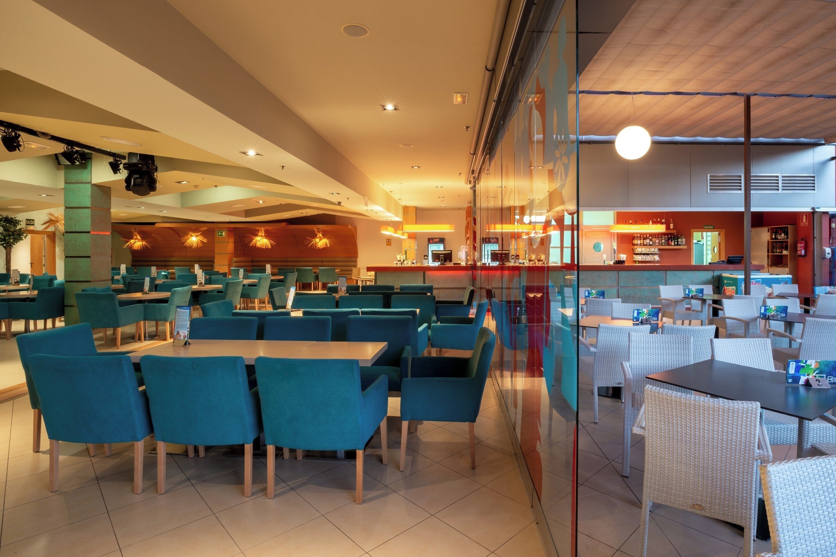 A spacious restaurant with high tables and chairs, a bar area, and a seating section with cushioned chairs.