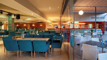 A spacious restaurant with high tables and chairs, a bar area, and a seating section with cushioned chairs.