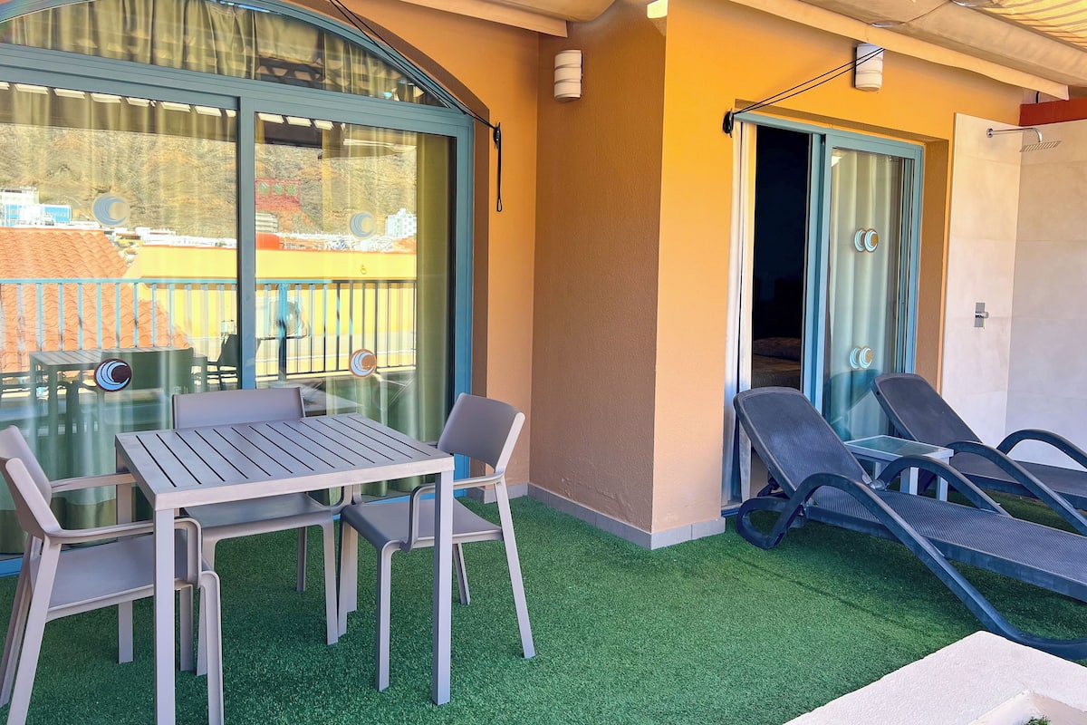 Un balcon avec une table et des chaises, une porte vitrée et un espace douche.