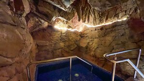 Zona de hidromasaje con paredes de piedra, una escalera metálica y una pequeña alberca.