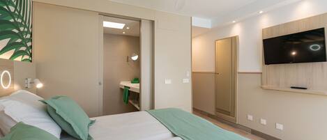 Een moderne hotelkamer met een bed, een televisie, een plafondventilator en een badkamer die door een open deur zichtbaar is.