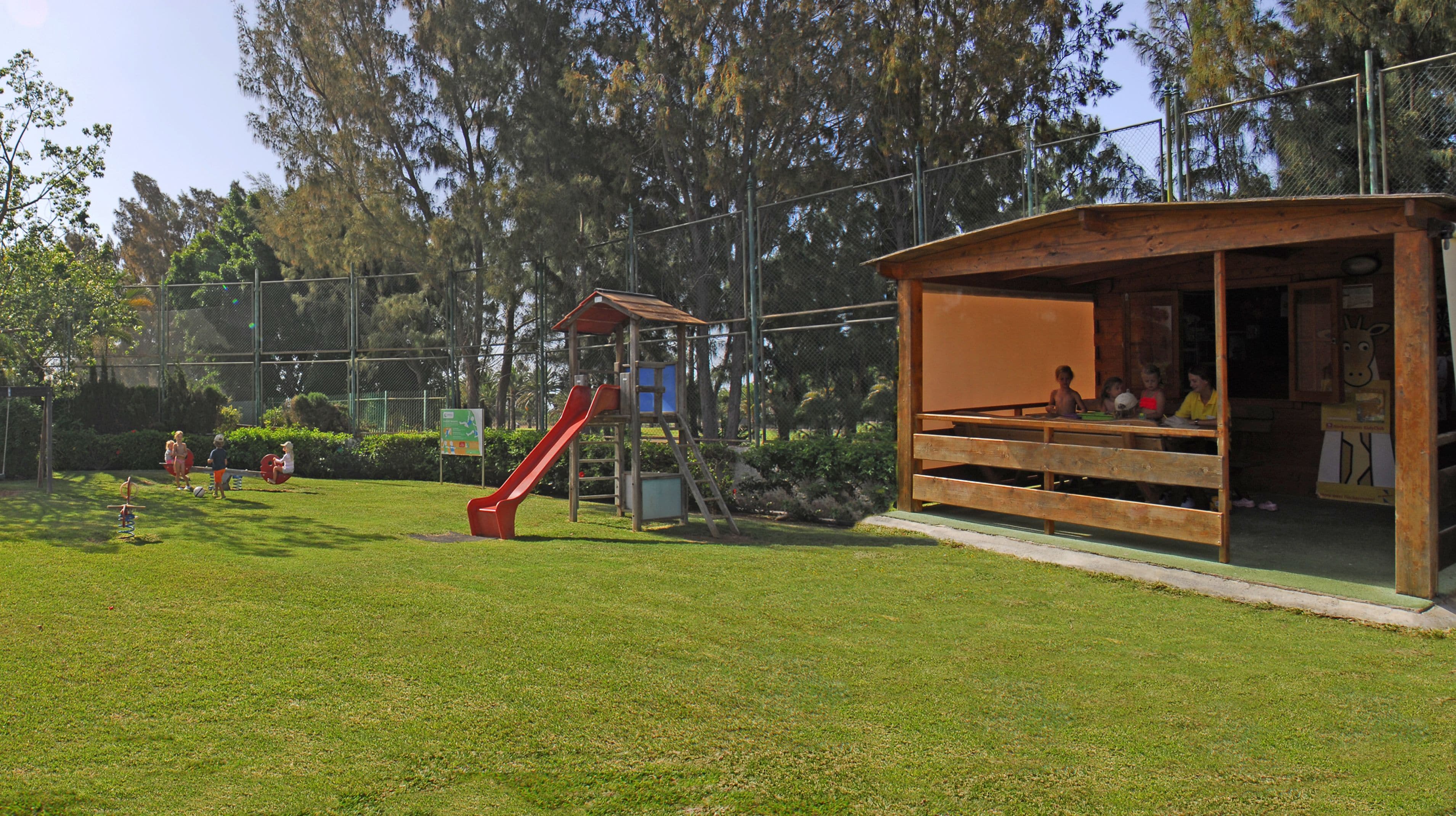 A playground with a slide and a covered seating area.