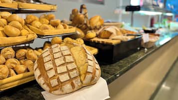 Mostrador de panadería con panes y pasteles variados.