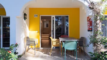 A yellow building with a number '170' sign, a staircase, and outdoor seating with chairs.