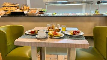 Una mesa de desayuno con platos de comida, una taza y un vaso de jugo.