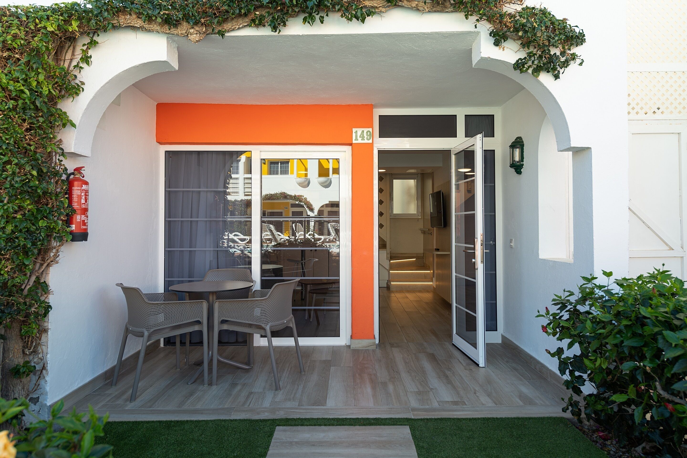 A hotel entrance with an orange awning, a fire extinguisher, and a number sign.