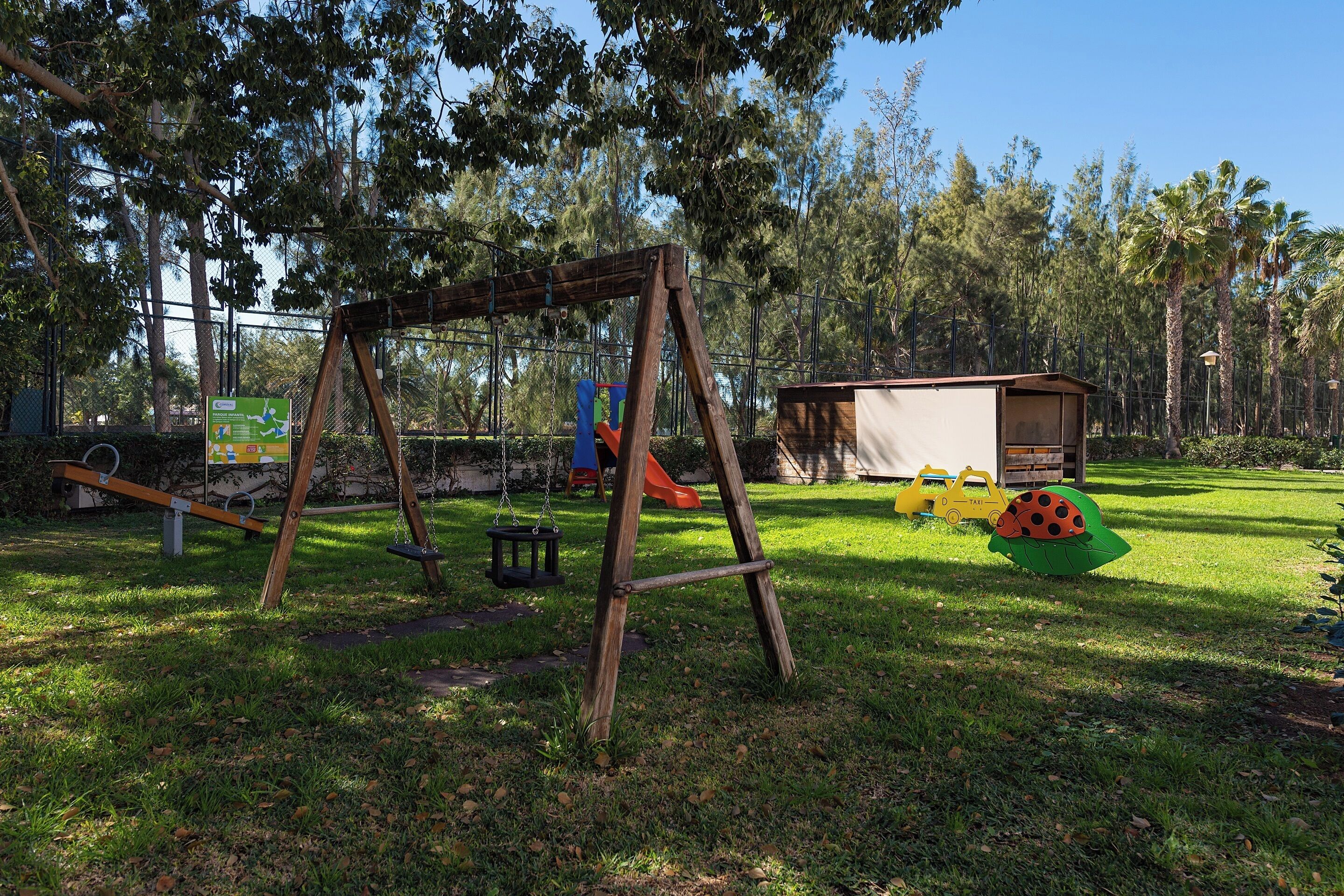 Un parque infantil con columpios, un tobogán y una casita de juegos.