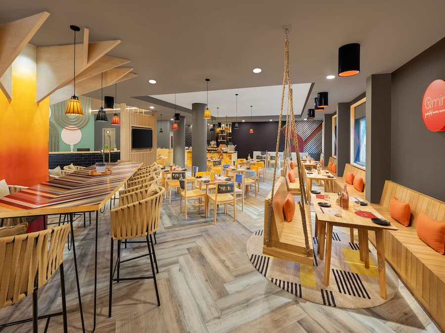 En modern restaurang med trämöbler, hängande lampor och en central bardisk.