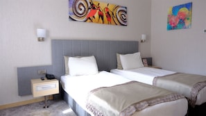 A hotel room with two beds, a nightstand, a telephone, and two paintings on the wall. - Midas Hotel (Ankara)