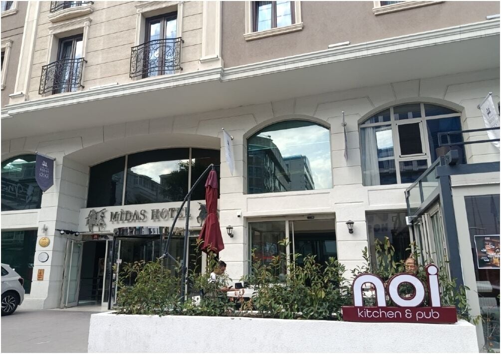 Un hotel con fachada moderna, entrada visible y letrero para cocina y pub.