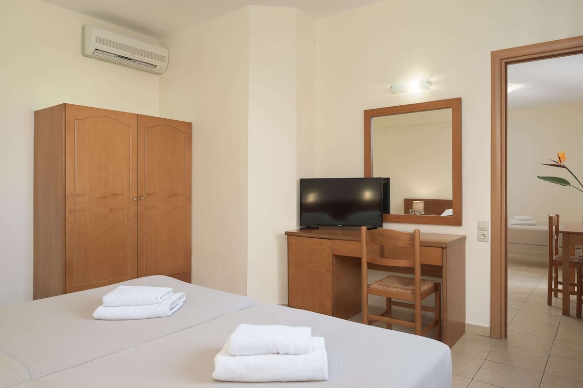 Een hotelkamer met een bed, een bureau met stoel, een televisie en een kledingkast.