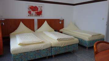 Una habitación de hotel con dos camas, cada una con cabecero de madera y colcha estampada. Encima de las camas hay un cuadro enmarcado en la pared.